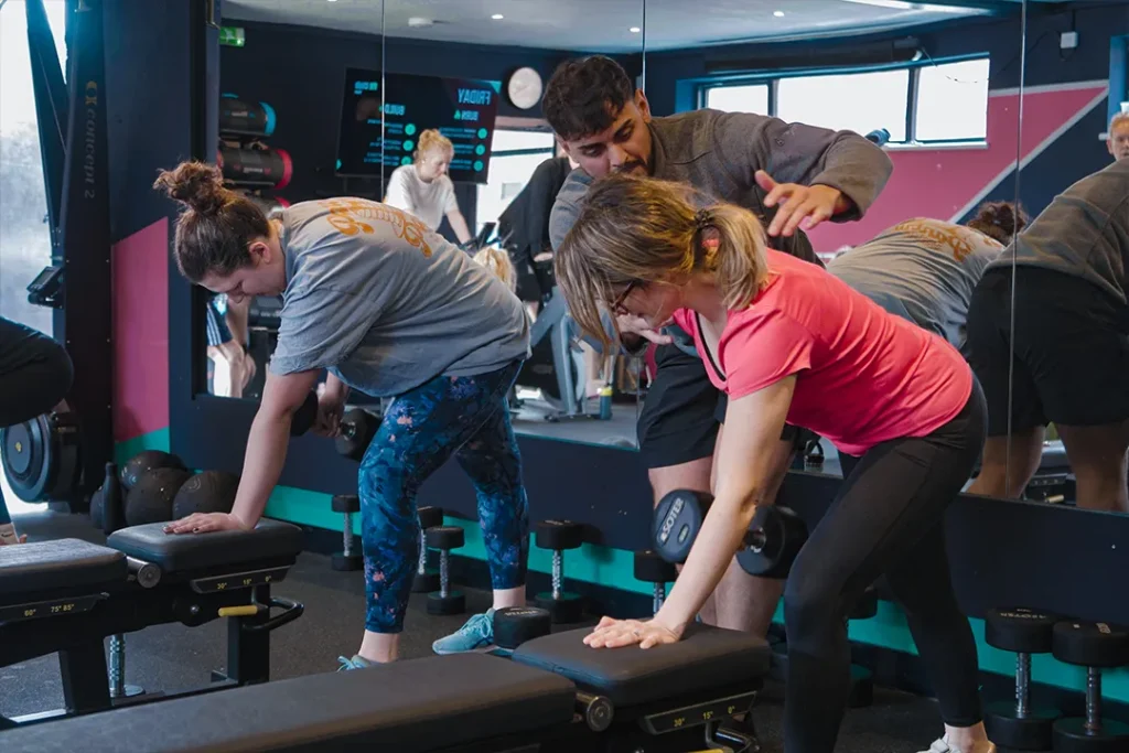 Fit Club York coach helping members with technique during a strength training workout